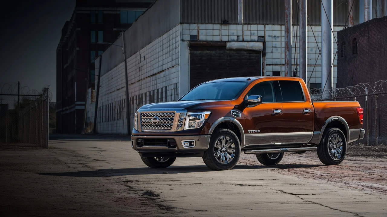 Orange Nissan Titan pickup parked by an industrial building