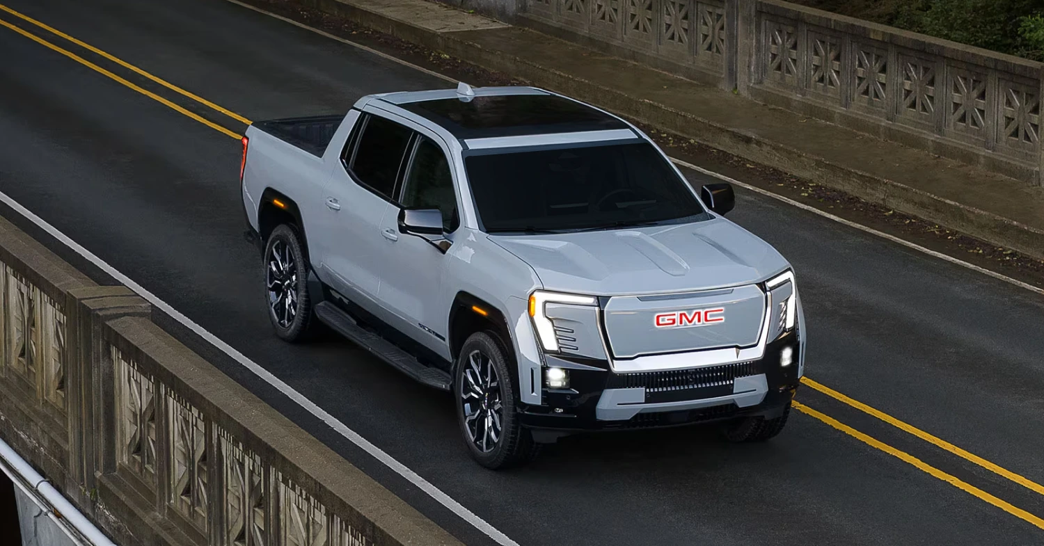 White GMC Sierra EV pickup driving across a bridge